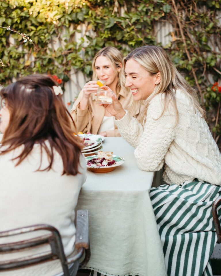 women laughing at dinner table 865x1081